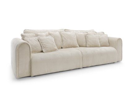 Rozkladacia pohovka SCANDORA XL SOFA v svetlom čalúnení, čelný pohľad s bohatým vankúšovaním a výrazným prešívaním na bielom pozadí.