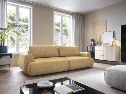 Rozkladacia pohovka VELORA SOFA v svetlom interiéri pri oknách, béžové čalúnenie, pohľad v uhle spredu.