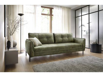 Rozkladacia pohovka CARINA v prevedení sofa zelená v modernom interiéri pri okne, čelný pohľad na štíhle nohy a bočnice.