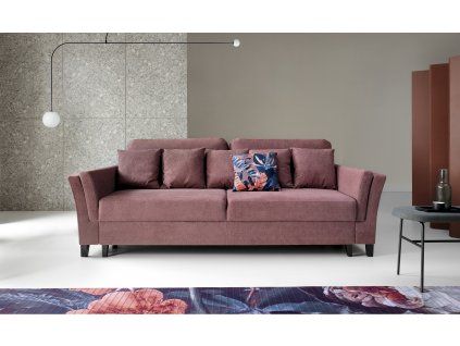 Rozkladacia pohovka VOLANS v staroružovej farbe v interiéri, pohľad spredu na sofa s vankúšmi pri sivej stene a dekoráciách.