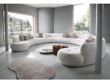 Sedacia súprava BLAZE sofa A3 XXL svetlá v modernom interiéri pri oknách, veľká oblúková zostava s okrúhlymi pufmi, pohľad spredu.