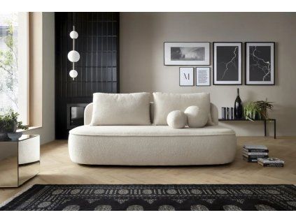 Rozkladacia pohovka ANTOL SOFA v svetlom interiéri pri stene s dekoráciami, krémové čalúnenie, pohľad spredu.