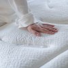Matrac COLLAGEN LUXURY, detail ruky pritláčajúcej mäkký prešívaný povrch poťahu, záber zhora.