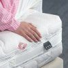 Matrac Swiss Exclusive – ukážka pružnosti, ruka pritláča vrchnú plochu matraca pri okraji, detail z boku.